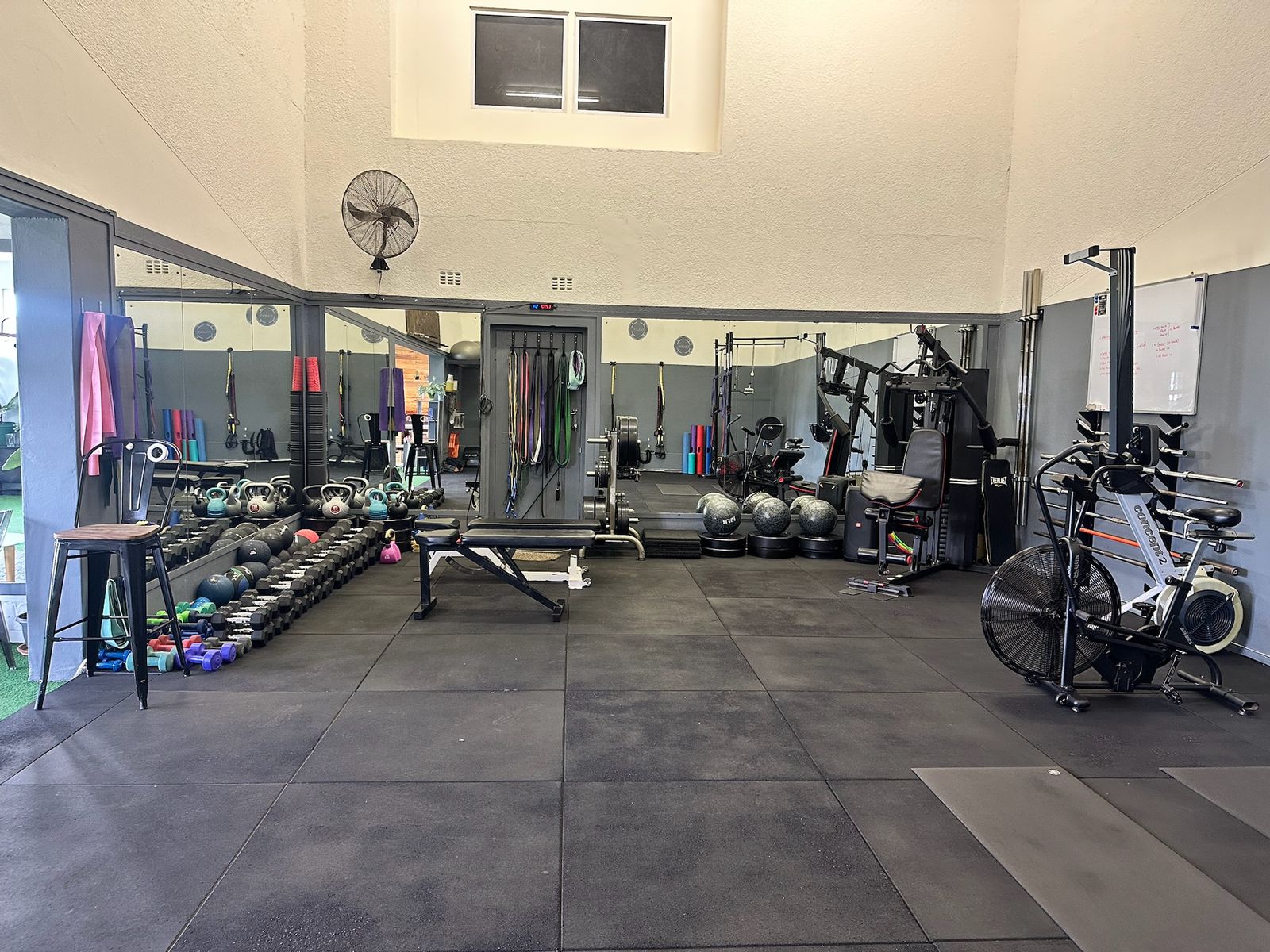 The main training floor, with kettlebells, dumbbells, a bench, medicine balls and an air bike along the walls.